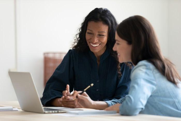 关闭 up happy young businesswoman using laptop with laughing female mentor