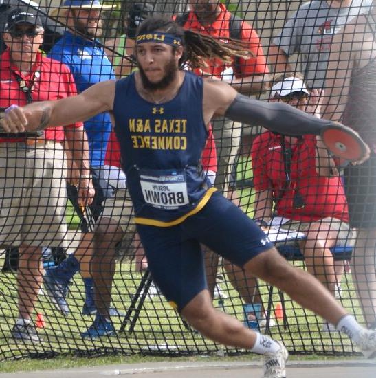 Athlete throws the discus with spectators watching in the background.